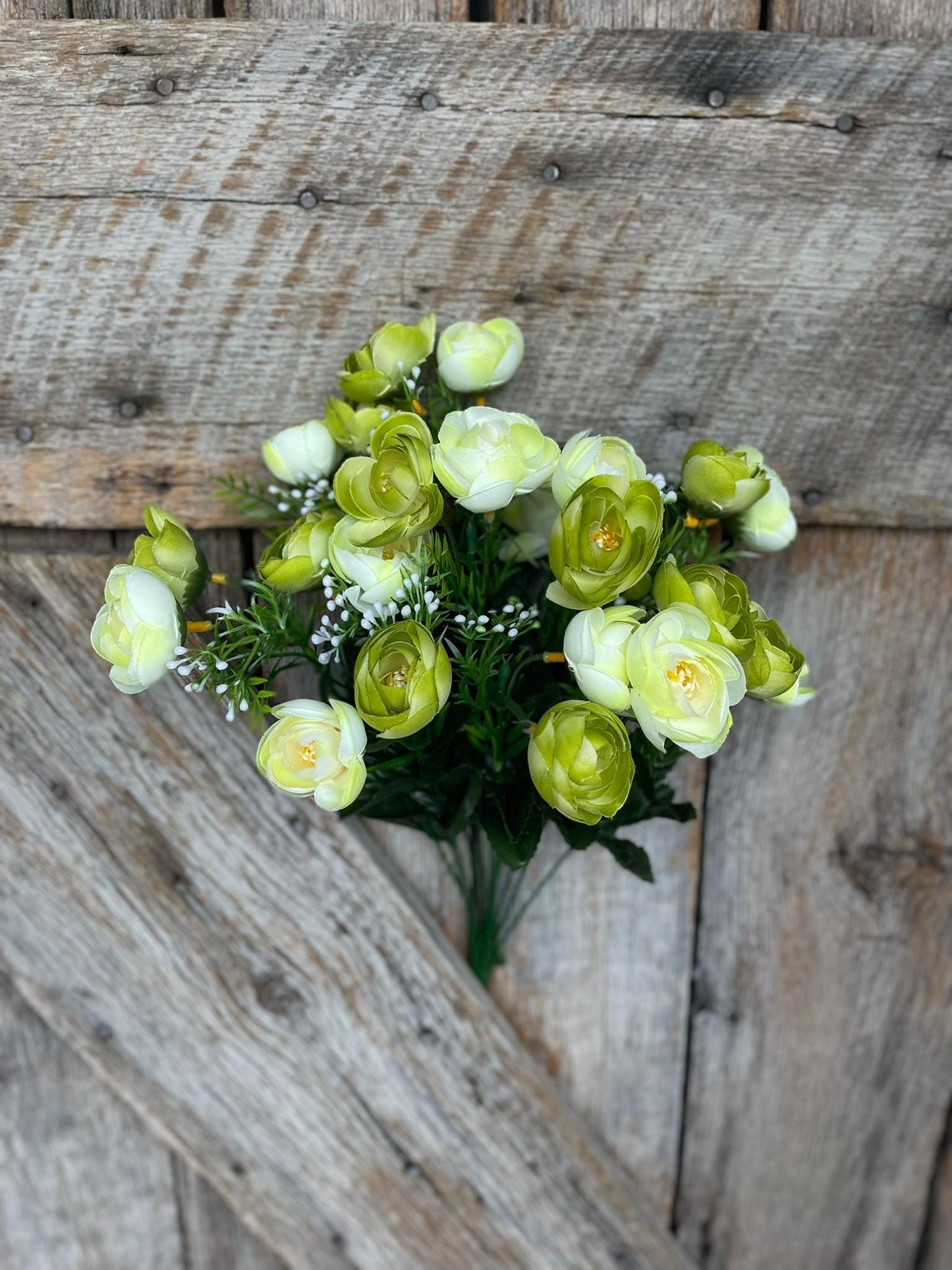 May include: A bouquet of artificial light green flowers with white centers. The flowers are arranged in a cluster with green leaves and stems.