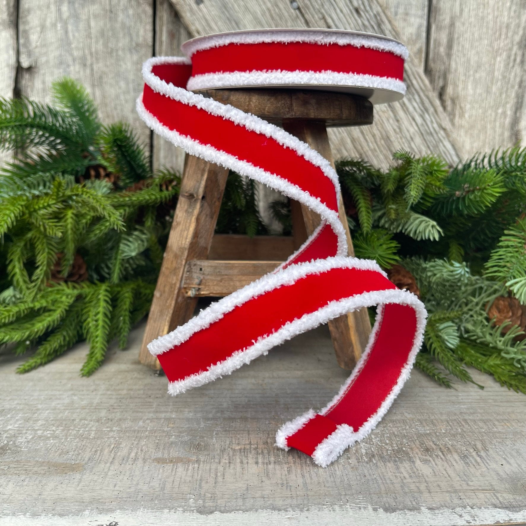 May include: Red velvet ribbon with white fuzzy trim. The ribbon is wrapped around a wooden stool.