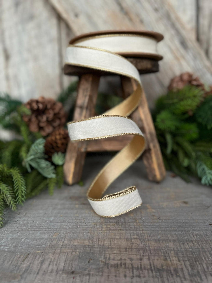 May include: A white velvet ribbon with a gold trim. The ribbon is wrapped around a wooden stool and is laying on a wooden surface.